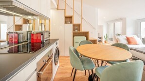 A modern kitchen with a dining area, a washing machine, and a staircase. - GuestReady - A charming place to stay in Lisbon (Lisbon)