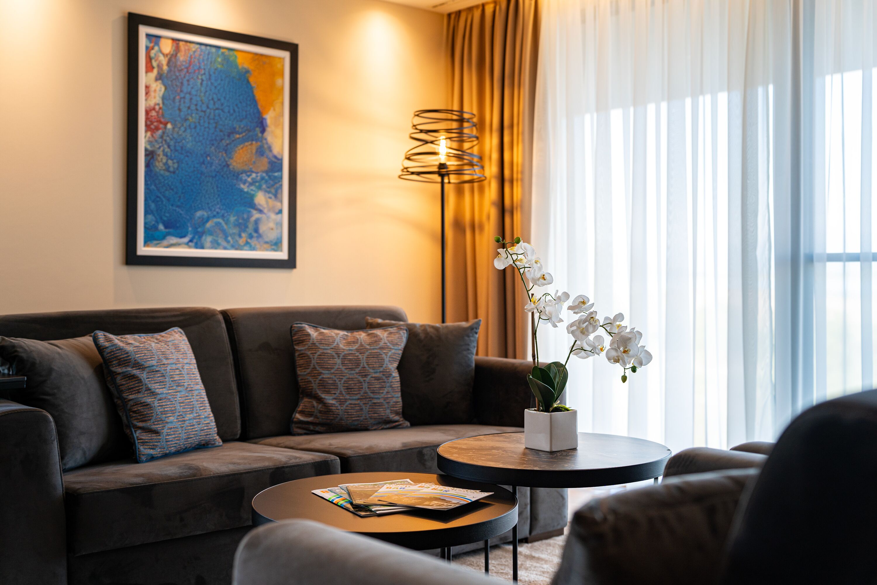Ein modernes Wohnzimmer mit einer Couch, einem Couchtisch und einer Stehlampe.