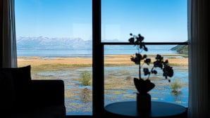 Et værelse med udsigt til strand og bjerge gennem store vinduer.