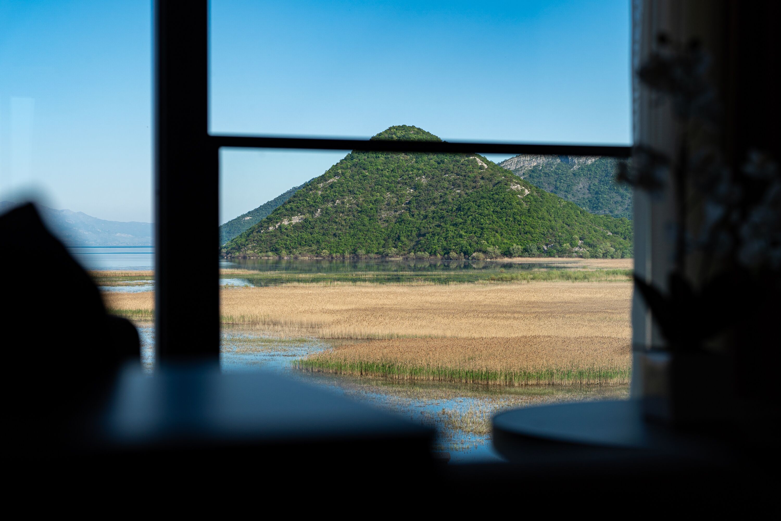 A view of a mountain through a window, with a river in the foreground.