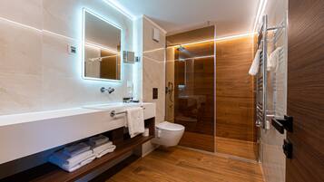 Un baño moderno con ducha de vidrio, tocador con espejo y suelo de madera.