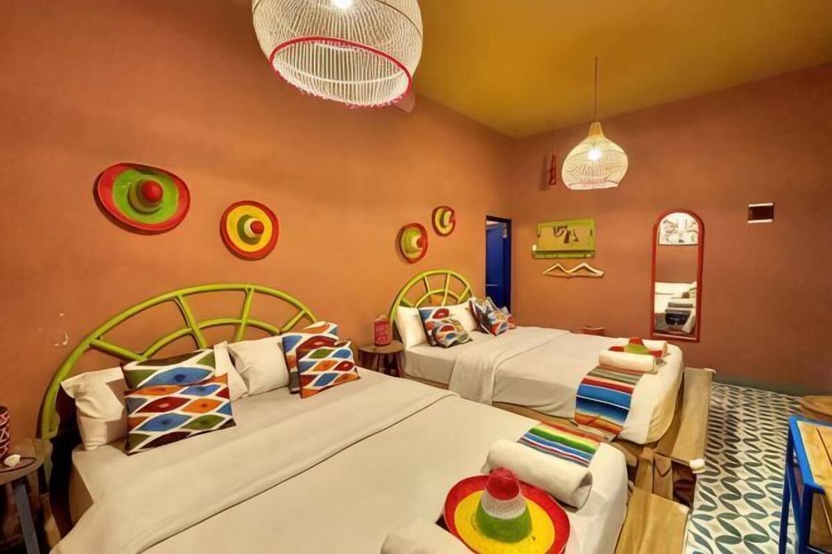 Una habitación con dos camas, una mesita y un espejo.