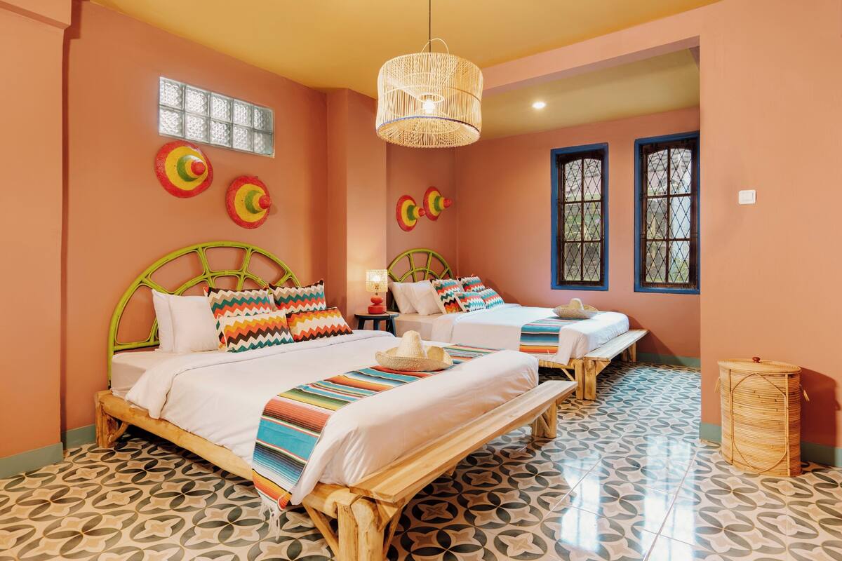 Una habitación con dos camas, una lámpara colgante tejida y baldosas de suelo estampadas.