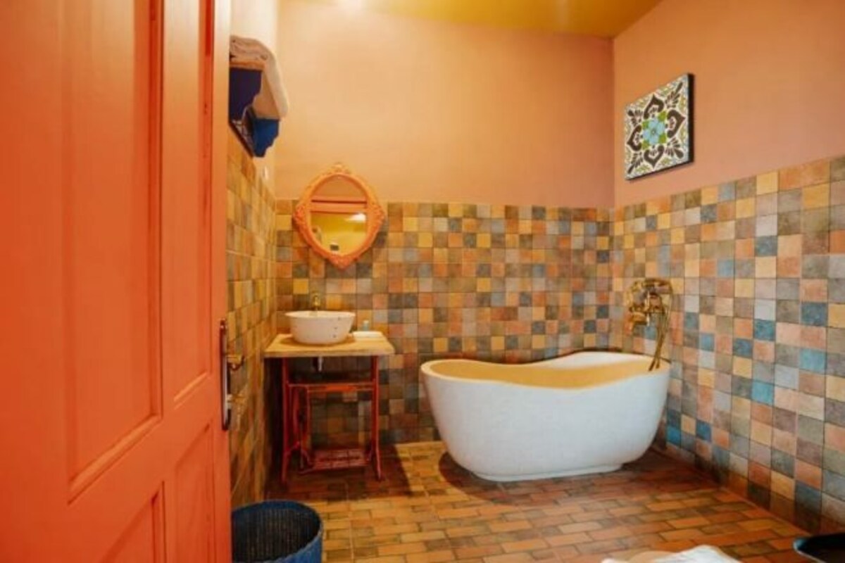 A bathroom with a freestanding bathtub, a sink with a mirror, and a tiled floor.