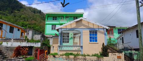 A two-story house with a balcony, a staircase, and a gate.