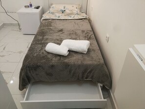 Cozy retreat with a single bed, bedside table, and storage unit.