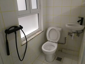 Bathroom features a white toilet, sink, and grid-patterned tiles.