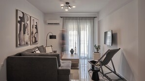 A modern living room with a grey sofa, a coffee table, and a TV mounted on the wall. - Vision Stournari 65 (Athens)