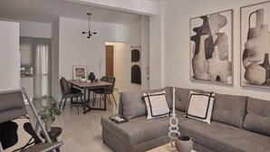 A modern living room with a grey sofa, a dining table, and abstract art on the wall. - Vision Stournari 65 (Athens)
