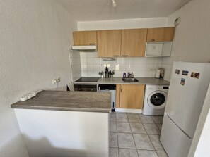 Compact kitchen with appliances, including a dishwasher and stove, and a small washing machine.