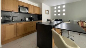 Une cuisine moderne avec des meubles en bois, un plan de travail noir et un coin repas comprenant une table et des chaises.