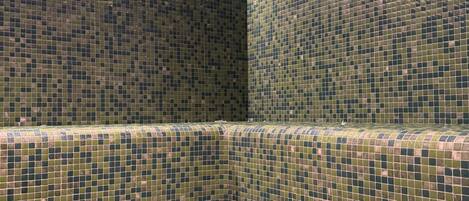 A tiled room with a seating area and a small ventilation vent.