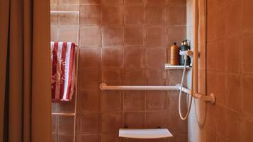 Een douchegedeelte met betegelde wanden, een handdoekhouder en een plank met toiletartikelen.
