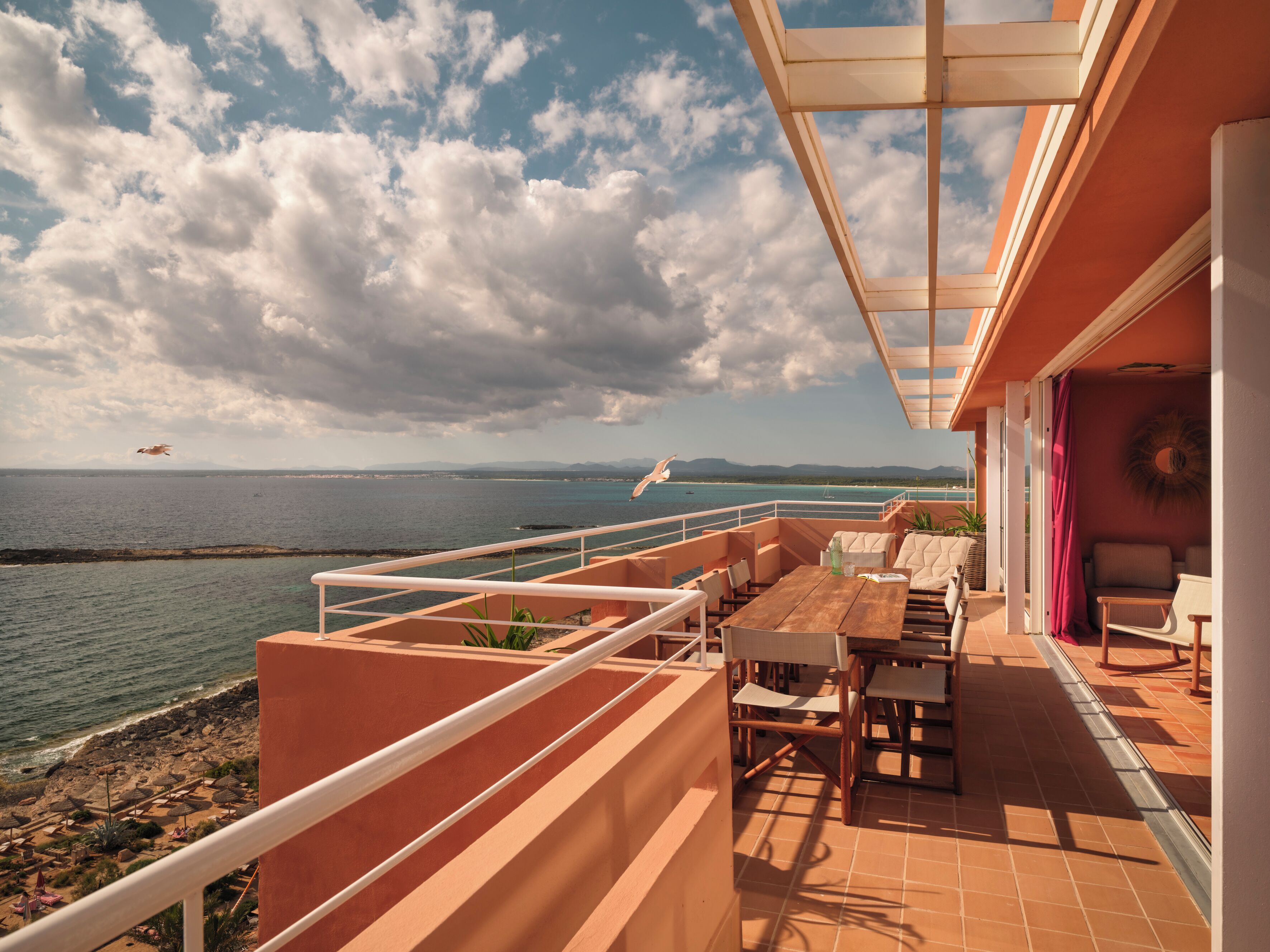 Una terraza con vista al mar, mobiliario exterior y barandilla.