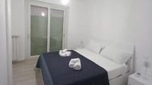 A bedroom with a bed, a nightstand, and a window with blinds.
