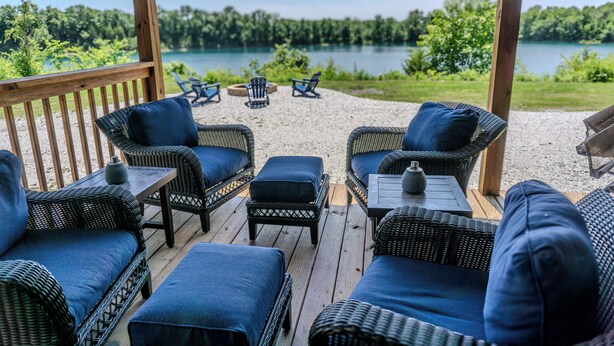 Eine Terrasse mit Korbmöbeln und Blick auf einen See.