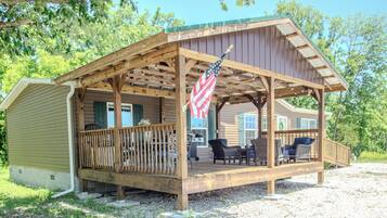 Une cabane en bois avec une véranda, des sièges d’extérieur et un drapeau américain.