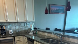 A kitchen with white cabinets, a stainless steel dishwasher, a double sink, and a granite countertop. - The Wharf resort Orange Beach with Waterpark included (Orange Beach)