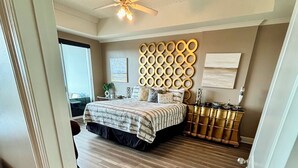 A bedroom with a bed, a ceiling fan, a decorative wall panel, and a dresser. - The Wharf resort Orange Beach with Waterpark included (Orange Beach)