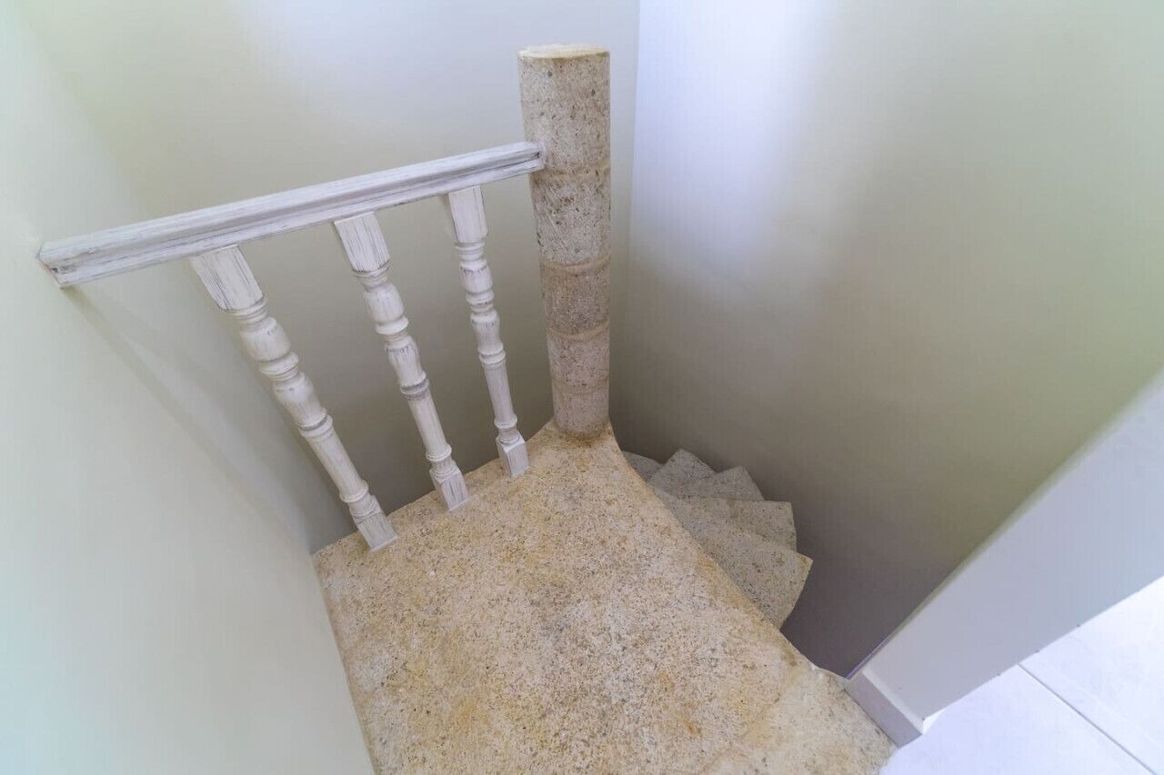 Eine Treppe mit weißen Balustern und einer Steinsäule.