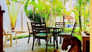 A patio area with a table and chairs, surrounded by tropical plants and a pool. - 11 Pax Comfort Pool Villa (Playa del Carmen)
