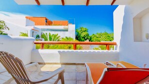 A balcony with a view of a modern building, a table, and two chairs. - 30 Pax 3 Connected Pool Villas (Playa del Carmen)