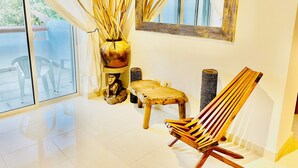 A modern interior with a large window, a wooden chair, a small stool, a decorative vase, and a mirror. - 8 Pax Basic Pool Villa (Playa del Carmen)
