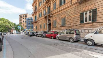 Una calle con coches estacionados y un edificio con numerosas ventanas y balcones.