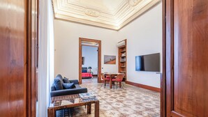 Ein Wohnzimmer mit einer Couch, einem Couchtisch und einem an der Wand befestigten Fernseher.