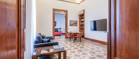 A living room with a sofa, a coffee table, and a TV mounted on the wall.