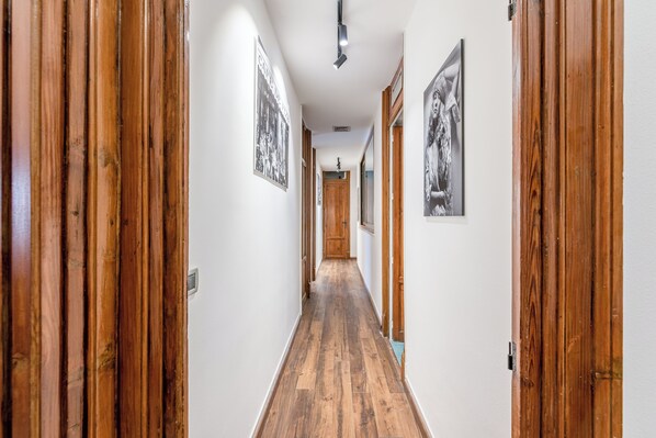 A hallway with wooden flooring and doors, leading to a room with a wooden door and a light fixture on the ceiling. - Lea's Art Apartment by Wonderful Italy (Palermo)