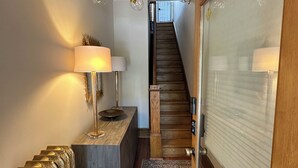 A hallway with a wooden staircase, a radiator, a patterned rug, and a chandelier. - Luxury townhome in Old town 2 blocks to King Street (Alexandria)