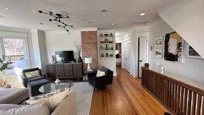 A modern living room with a TV, sofas, a coffee table, and a fireplace. - Luxury townhome in Old town 2 blocks to King Street (Alexandria)