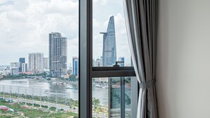 A hotel room with a large window offering a city view, a bed, and a curtain. - The Opera Residences (Ho Chi Minh City)