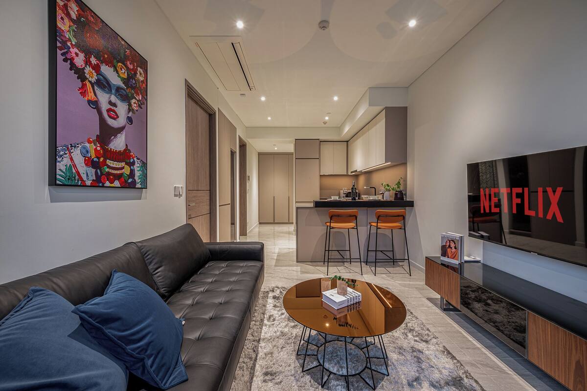 Uma sala de estar moderna com um sofá de couro, uma mesa de centro e uma televisão de tela plana grande.