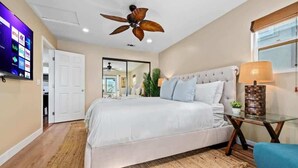 A bedroom with a bed, a ceiling fan, a TV on the wall, and a window with blinds. - MB Oceanviews and Rooftop Deck 2BR w/ Parking (San Diego)