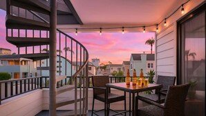 A balcony with a spiral staircase, wicker furniture, and bottles on a table. - MB Oceanviews and Rooftop Deck 2BR w/ Parking (San Diego)