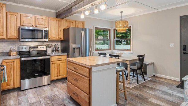 A modern kitchen with wooden cabinets, stainless steel appliances, and a central island. - Walk Downtown - Fall Colors, Wineries & Firepit (Boyne City)