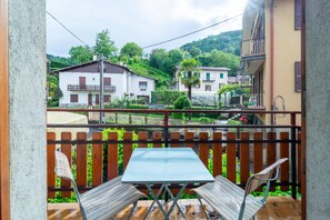 Un balcon avec une table et des chaises, donnant sur un quartier résidentiel avec des maisons et de la verdure.