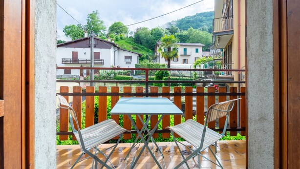 Un balcón con mesa y sillas, con vista a una zona residencial con casas y vegetación.