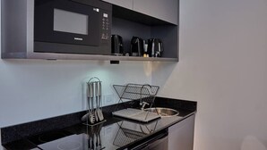 A modern kitchen with a black microwave, coffee maker, and kettle on the countertop. - Céntrico Studio Para 2 Personas (Buenos Aires)