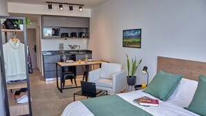 A modern hotel room with a bed, a desk, a chair, a small table, a laptop, and a nightstand with a lamp. - Céntrico Studio Para 2 Personas (Buenos Aires)