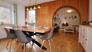 Un comedor moderno con una mesa y sillas de madera, una cocina al fondo y vistas a través de un arco.