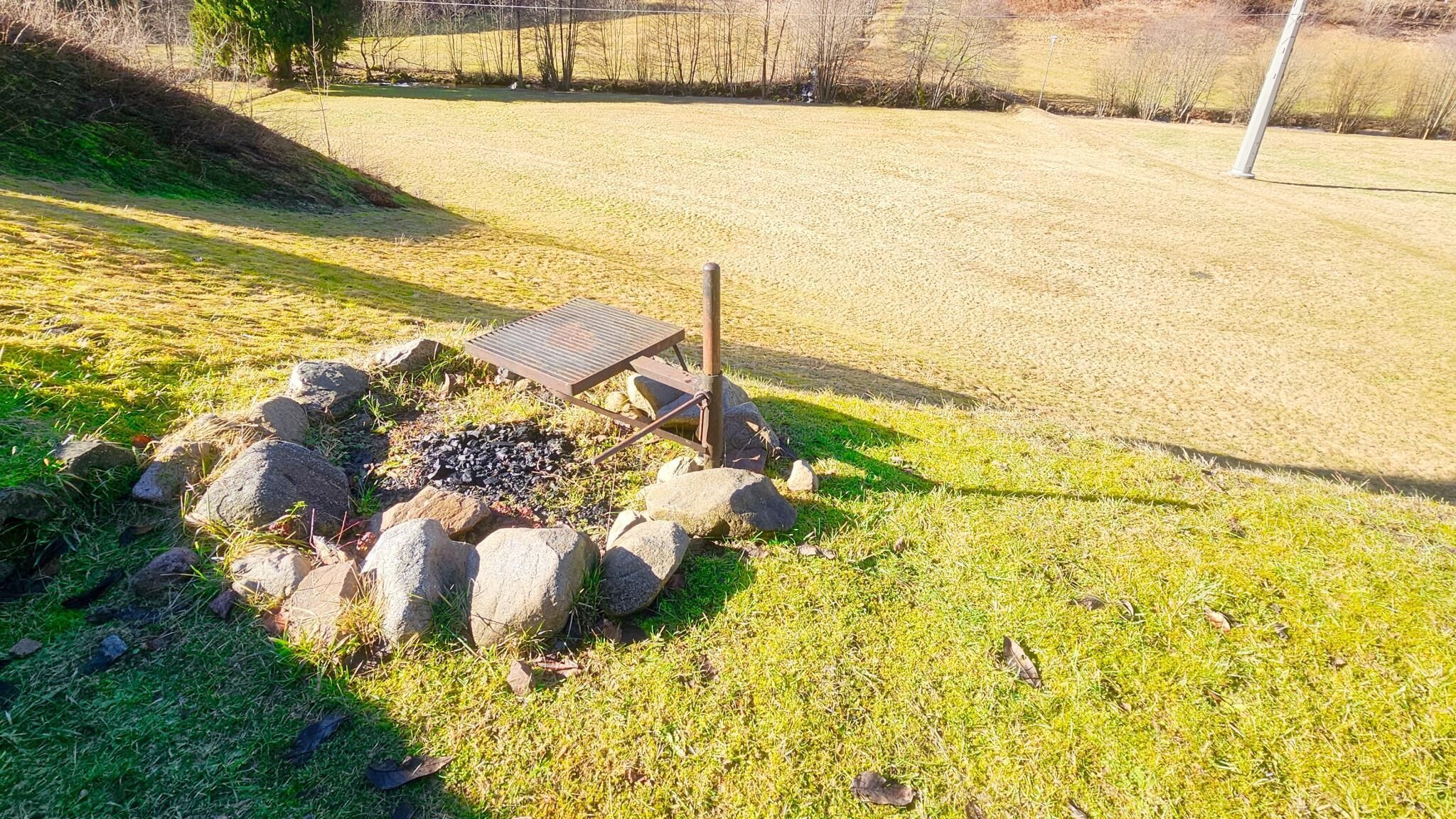 A picnic area with a metal table and benches, surrounded by rocks and grass.