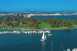 A marina with boats, a bridge in the background, and a green landscape.