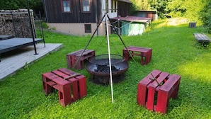 A backyard with a fire pit, red benches, and a wooden deck. - Vacation home time out from everyday life (Kirchenkirnberg)