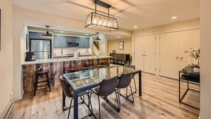 A modern kitchen with a central island, bar stools, and a dining table with chairs. - Modern Mountain Getaway with Stunning Views (Keystone)