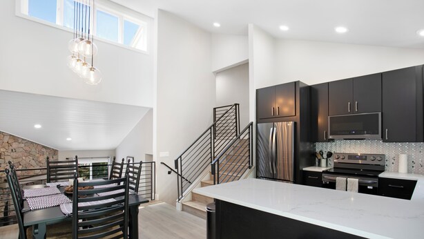 A modern kitchen with dark cabinets, stainless steel appliances, and a large island.