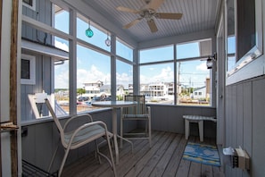 Relax on the covered deck with a ceiling fan, surrounded by large windows offering views of the neighborhood.