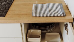 Cocina con encimera de madera, electrodoméstico azul y armarios de almacenamiento blancos.
